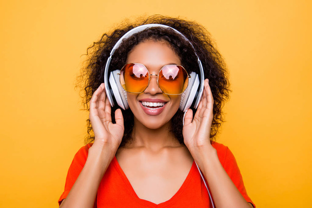 Head shot portrait of cheerful positive girl in summer glasses with headphones on head listening favorite pop music isolated on yellow background - Fotoğraf, Görsel