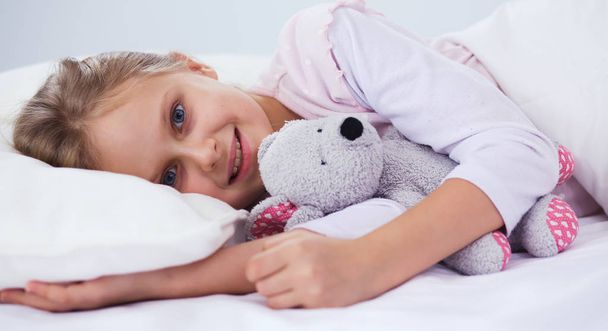 Child little girl sleeps in the bed with a toy teddy bear. - Zdjęcie, obraz