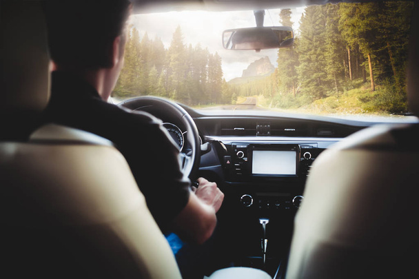 egy ember a vezetés egy autó az úton, az erdő és a hegyek a háttérben - Fotó, kép