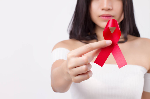 Kobieta ręka trzyma czerwoną wstążką łuku, hiv lub aids świadomości symbol przedstawiony przez kobietę w studio strzał. medycznych, miłości, pozyskiwania funduszy koncepcja czerwoną wstążką hiv aids dzień świadomości - Zdjęcie, obraz