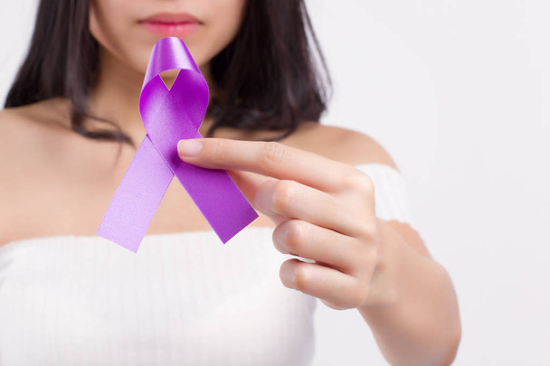 vrouw hand met paarse lint boog, lupus Lse of alzheimer bewustzijn symbool; paarse lint voor medische, liefdadigheid fondsenwerving concept voor lupus, of alzheimer patiënt of preventie - Foto, afbeelding