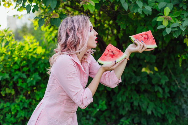 Beautiful young woman with pink hair holding two slices of sweet juicy watermelon - Foto, afbeelding