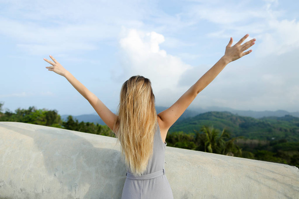 Young girl with outstretched hands standing in mountains background. - Foto, immagini