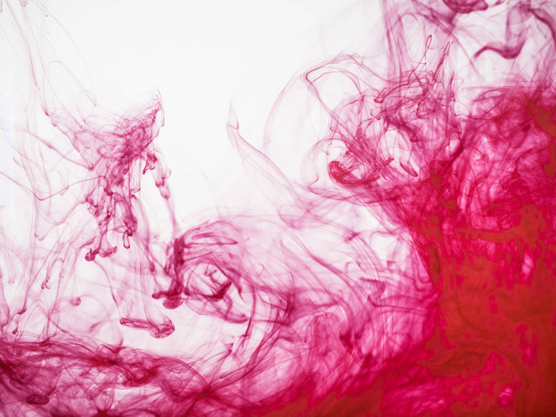 Close up view on red acrylic ink under water. Red acrylic ink explosion, abstract background. Colourful splash of paint dissolving into water. Abstract acrylic background. - Foto, Imagen