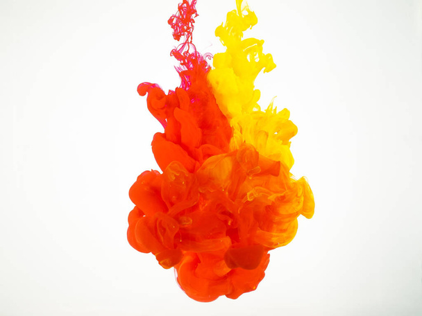 Abstract background of yellow and red splash of ink in water. Cloud of silky ink in water isolated on white background. Ink swirling in water. The paint dissolving into water. - Fotó, kép