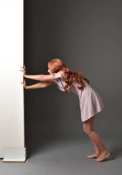 portrait complet de fille, portant une robe d'été pourpre, appuyé sur un mur. fond studio gris
. - Photo, image