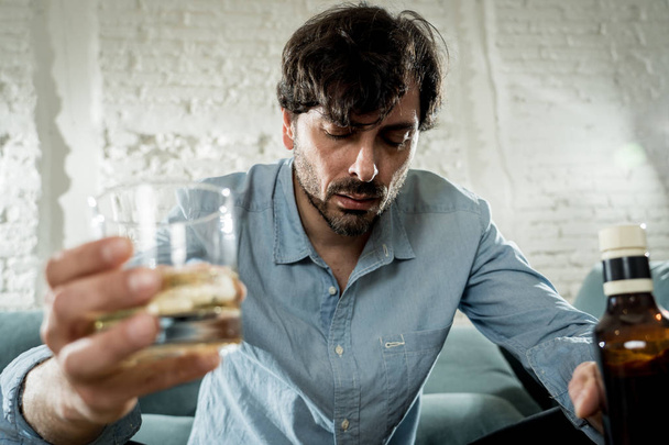 drunk alcoholic lain business man drinking whiskey from the bottle and glass depressed wasted and sad at home couch in alcohol abuse and alcoholism concept - Fotoğraf, Görsel