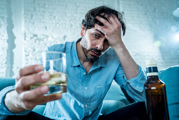 drunk alcoholic lain business man drinking whiskey from the bottle and glass depressed wasted and sad at home couch in alcohol abuse and alcoholism concept - Foto, imagen
