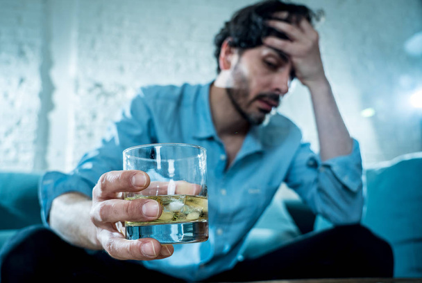 drunk alcoholic lain business man drinking whiskey from the bottle and glass depressed wasted and sad at home couch in alcohol abuse and alcoholism concept - Photo, image