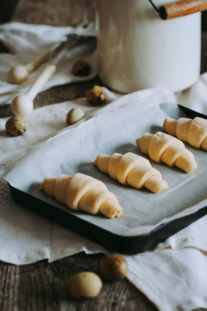 Croissants de hojaldre casero en bandeja para hornear, engrasado con huevo
 - Foto, imagen