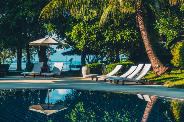Hermosa piscina al aire libre de lujo con sombrilla y silla en hotel y resort para viajes y vacaciones
 - Foto, Imagen