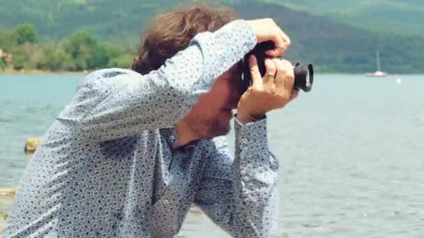 Mężczyzna przed jeziorem na wakacjach robi zdjęcia przyrodzie i zwierzętom zbliżenie - Materiał filmowy, wideo