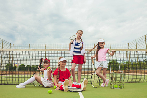 Portrait of group of girls as tennis players holding tennis racket against green grass of outdoor court - Foto, Imagem