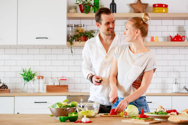 Picture of beautiful loving couple cooking vegetables in kitchen at apartment - Foto, Bild