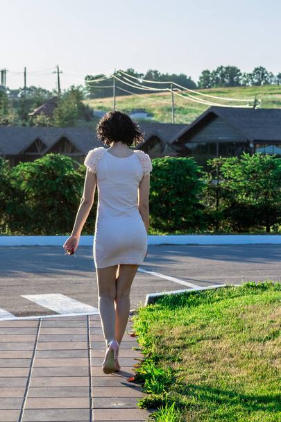 Back view of Young adult woman wearing sexy pink dress and walking street in perspective . - Photo, Image