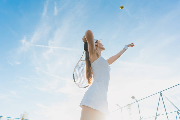 Woman serving the ball for a game of tennis - Photo, Image