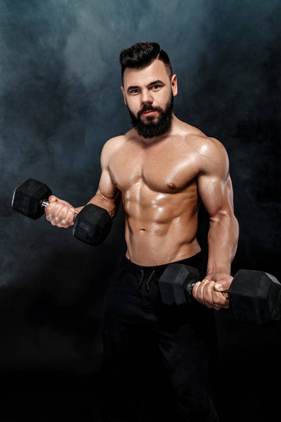 athletic muscular man doing exercises with dumbbells. - Fotoğraf, Görsel