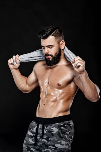 bodybuilder with towel on black background - Foto, Bild