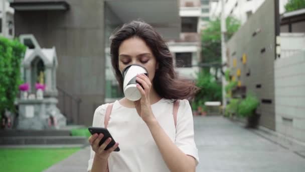 girl walking on city streets and drinking coffee to go in super slow motion - Video