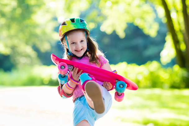 Child riding skateboard in summer park. Little girl learning to ride skate board. Active outdoor sport for school and kindergarten kids. Children skateboarding. Preschooler on longboard. Kid skating. - Photo, Image