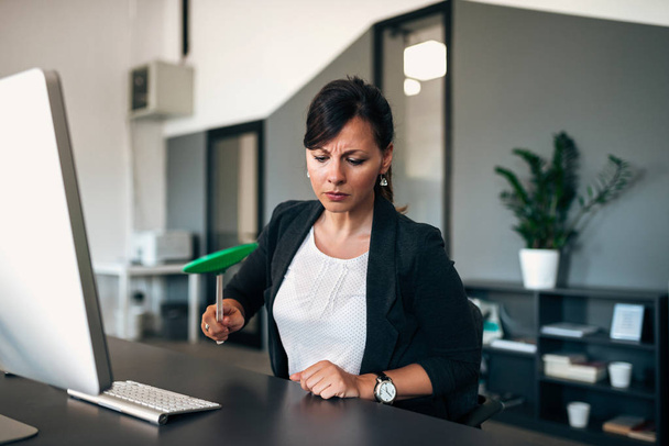 Annoyed businesswoman hitting a fly with flyswatter. - Foto, afbeelding