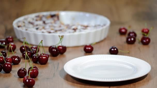 Piece of homemade yummy clafoutis pie with whole cherries on brown plate - Footage, Video