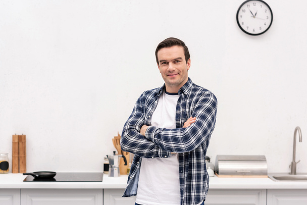 heureux homme adulte avec les bras croisés à la cuisine regardant caméra
 - Photo, image