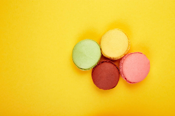 Sweet Dessert Macaron or macaroon on yellow paper background, colorful almond cookies, cakes. Greeting card. Woman Day or Mother Day. Spring. Flat lay. Copy space. Minimalism - Photo, Image