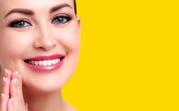 Pretty woman with smooth and soft skin smiling to you, isolated on yellow background - Photo, Image