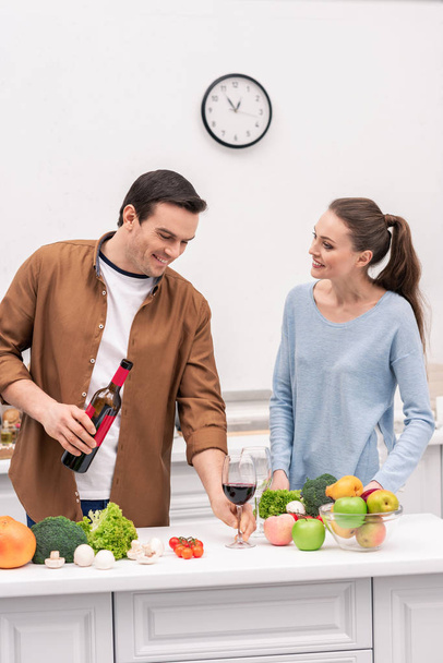happy adult couple with red wine cooking together at kitchen - Zdjęcie, obraz