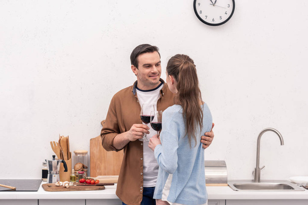 hermosa pareja de adultos tintineo vasos de vino en la cocina
 - Foto, Imagen