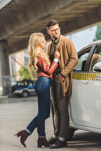 happy stylish young couple standing together near taxi cab - Fotoğraf, Görsel