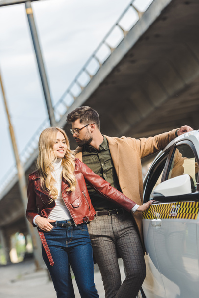 beautiful stylish young couple standing together near taxi cab - Valokuva, kuva