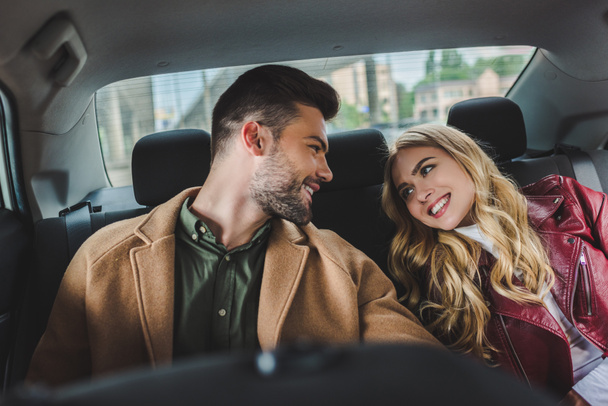 beautiful happy young couple smiling each other while sitting together in car - Φωτογραφία, εικόνα