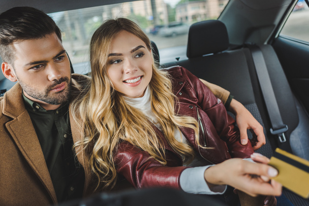 stylish young couple sitting together in taxi, girl holding credit card - Foto, immagini