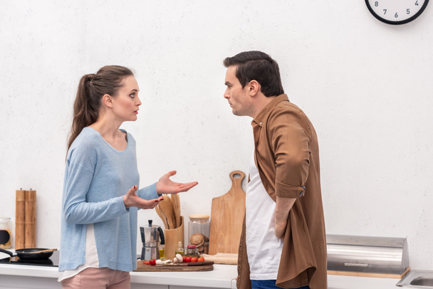 side view of adult couple having quarrel at kitchen - Photo, Image