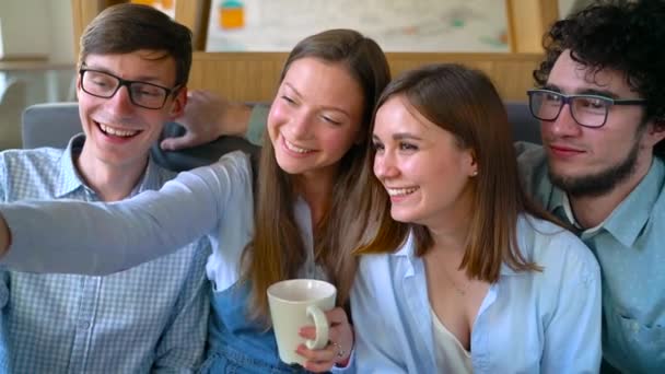 Amigos sonrientes se sientan en un café, se divierten comunicándose y hacen selfies. Movimiento lento
 - Imágenes, Vídeo