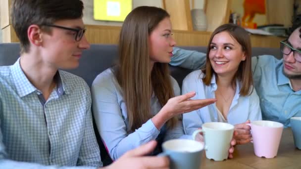 Jovens amigos se sentam em um café, bebem café e se divertem se comunicando
 - Filmagem, Vídeo
