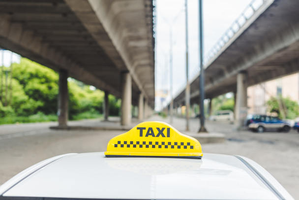 lähikuva keltaisesta taksimerkistä ohjaamon päällä
 - Valokuva, kuva