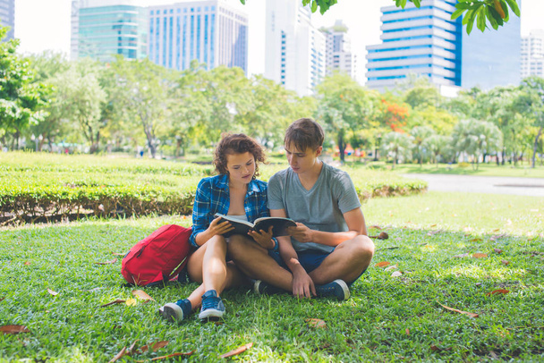 Students reading a book and sitting in the park - Photo, Image