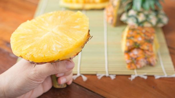 Ananas met plakjes - menselijke vrouw handen houden ananas segmenten. Tropisch fruit concept. Close-up, selectieve aandacht. - Foto, afbeelding