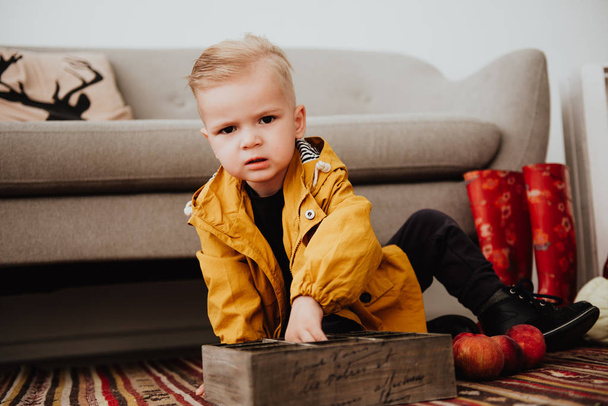 Cool moderno hipster menino 2 anos de idade usa casaco amarelo posando na fotozona decorada de decoração de outono com belas folhas brilhantes de outono. Atmosfera acolhedora
 - Foto, Imagem