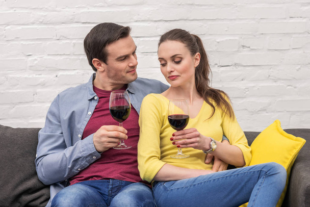 beautiful adult couple with glasses of red wine spending time together at home - Photo, Image