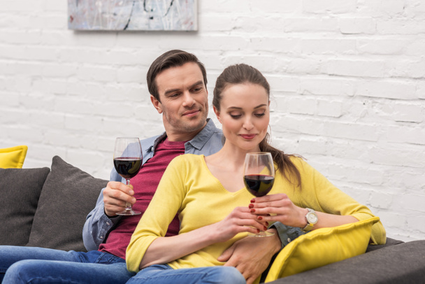 happy adult couple with glasses of red wine spending time together at home - Foto, Bild