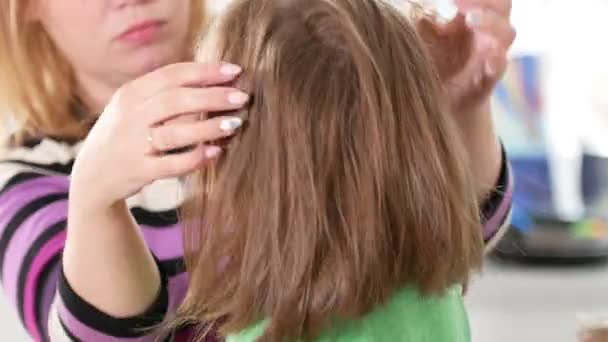 Zorgzame moeder is het kammen van haar haar dochtertje - Video