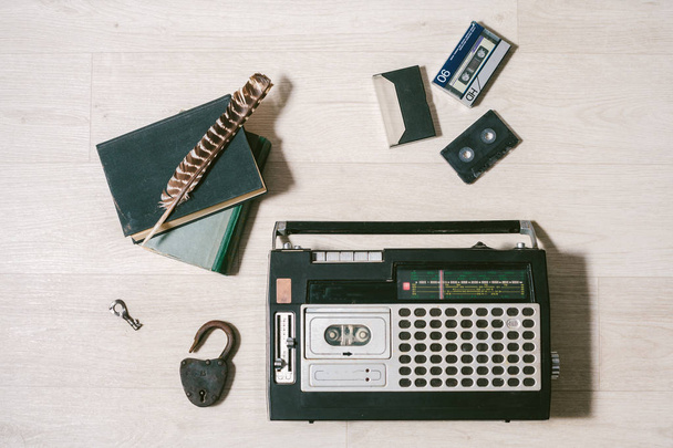 stary magnetofon kasetowy, klucz, blokady, książek i pióro na drewniane białe tło. Widok z góry. LAYFLAT - Zdjęcie, obraz