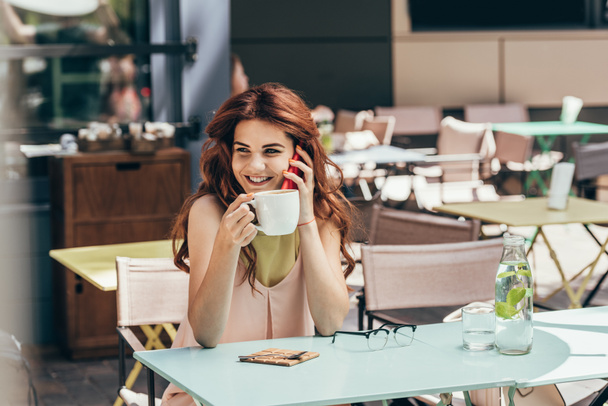 Portret kobiety uśmiechający się filiżankę kawy rozmowy na smartfonie w kawiarni - Zdjęcie, obraz