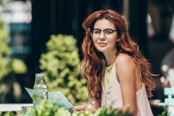 Μερική άποψη του ελκυστική νεαρή γυναίκα σε γυαλιά με εφημερίδα στο εστιατόριο - Φωτογραφία, εικόνα