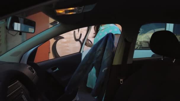 Woman put a jacket on the car seat and sits down on the drivers seat, intending to start the engine - Séquence, vidéo