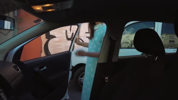 Kadın araba koltuğunda bir ceket koymak ve motoru çalıştırmayı planlayan şoför koltuğunda oturur - Video, Çekim